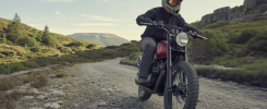 Motard expérimentant la conduite sur un chemin boueux et rocailleux dans les paysages sauvages du nord du Pays de Galles, avec montagnes et forêts en arrière-plan