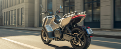 Moto électrique Can-Am Pulse 2025 argentée, vue latérale sur fond urbain moderne