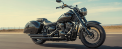 Kawasaki Vulcan 900 customisée avec un sidecar noir brillant sur route, vue latérale dynamique d'une moto cruiser classique transformée en sidecar avec détails métalliques et finition soignée